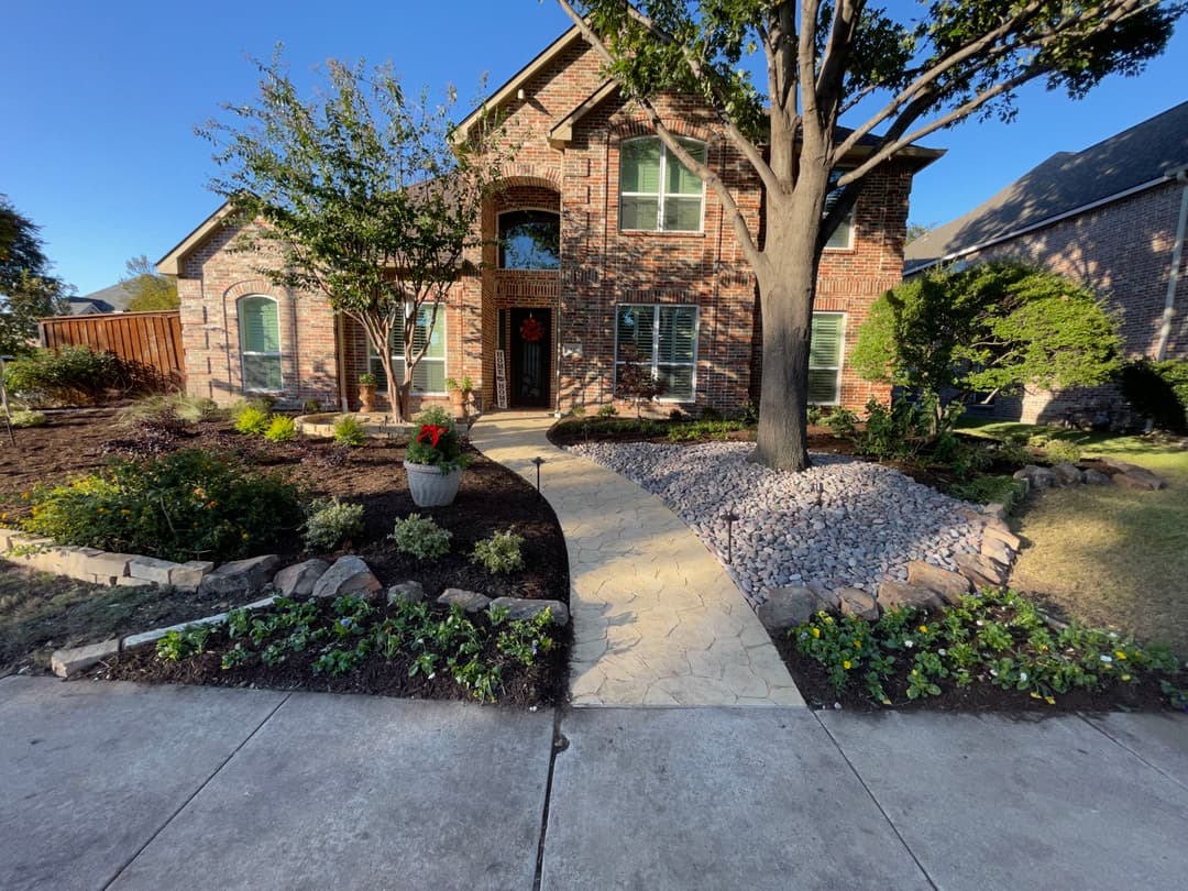 Charming brick house with landscaped garden, pathway, and seasonal decor.