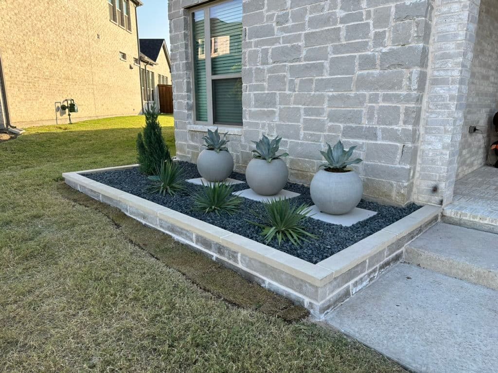 Modern house landscaping with three round planters, succulents, and decorative stones.